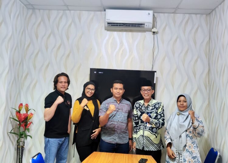 Ketua HIPMI Peduli Sleman dan Kepala Dinas Sosial Sleman berjabat tangan sebagai simbol kerjasama.